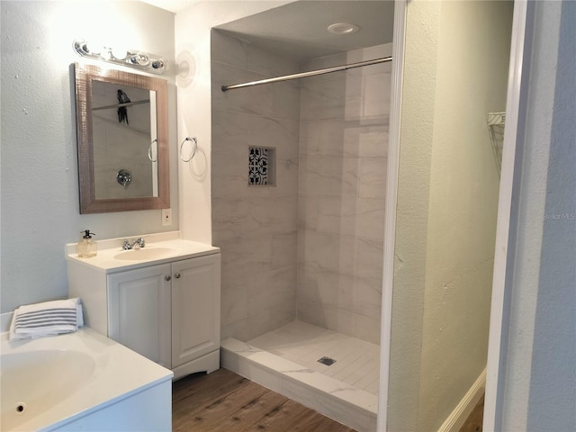 bathroom with tiled shower, vanity, and hardwood / wood-style flooring