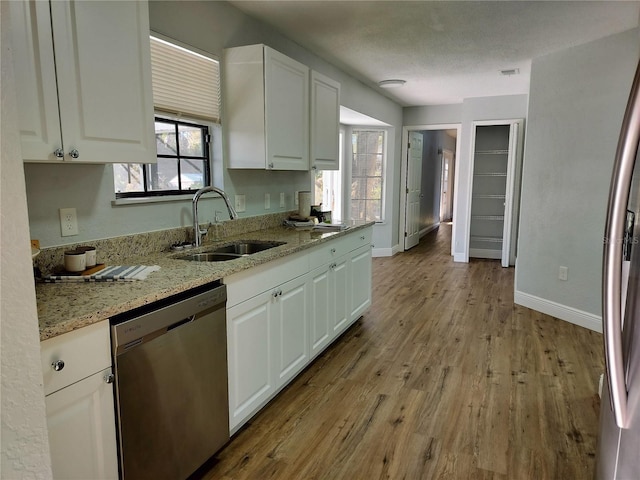 kitchen featuring sink, stainless steel appliances, light stone counters, white cabinets, and light wood-type flooring