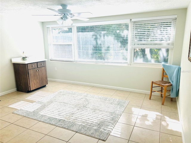 interior space featuring ceiling fan, plenty of natural light, light tile patterned flooring, and a textured ceiling