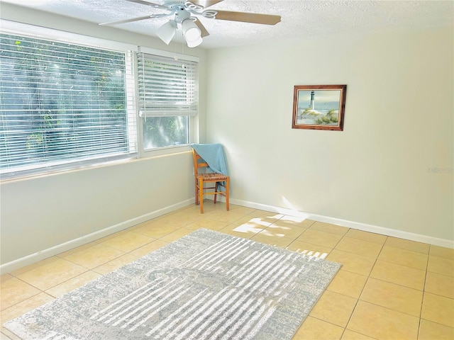 living area with a textured ceiling, ceiling fan, and light tile patterned floors