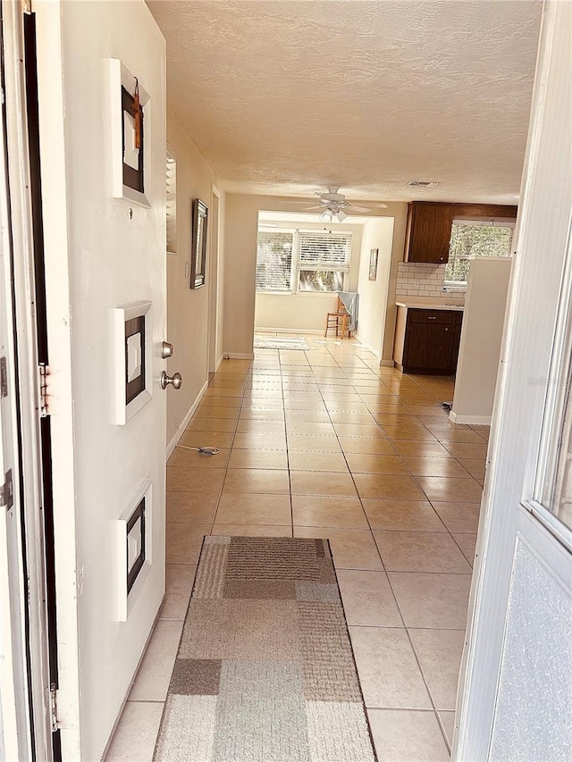 hall with light tile patterned floors and a textured ceiling