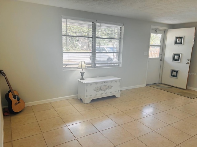 doorway with a textured ceiling and light tile patterned floors