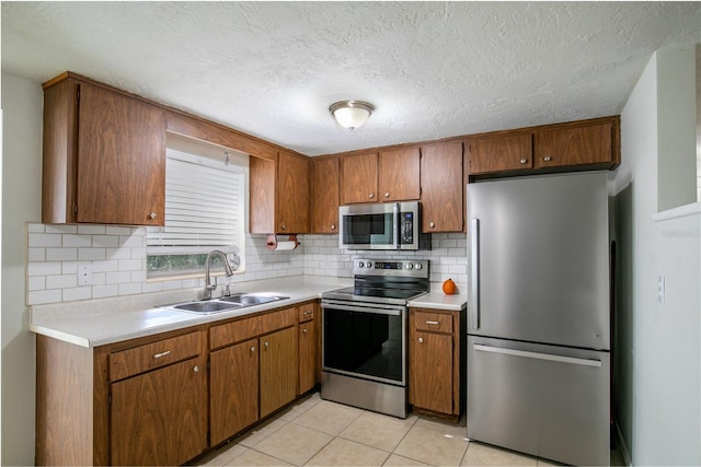 kitchen featuring light tile patterned floors, stainless steel appliances, backsplash, a textured ceiling, and sink