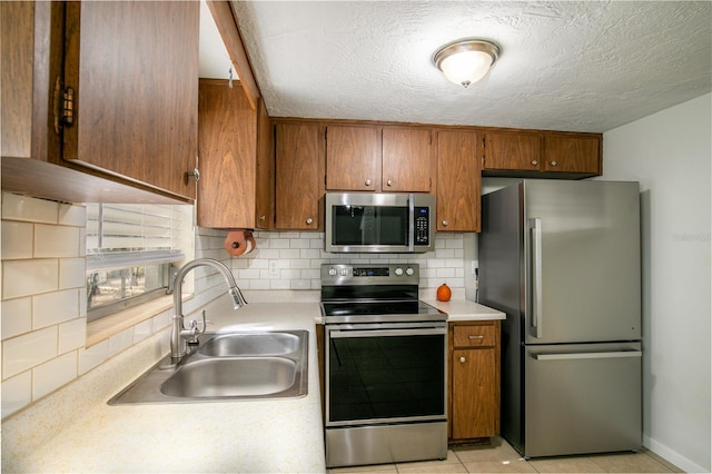 kitchen featuring tasteful backsplash, appliances with stainless steel finishes, sink, and a textured ceiling