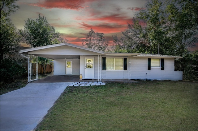 ranch-style home featuring a carport and a lawn