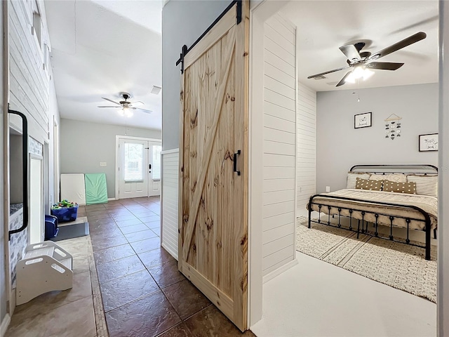 bedroom with ceiling fan and a barn door