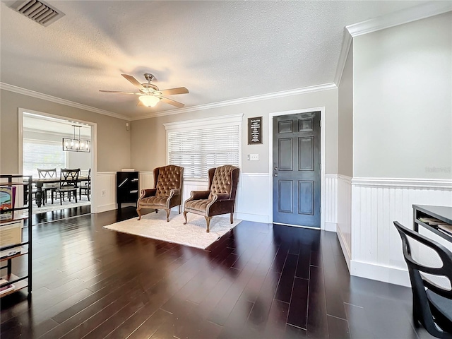 living area with a textured ceiling, dark hardwood / wood-style floors, ceiling fan, and crown molding