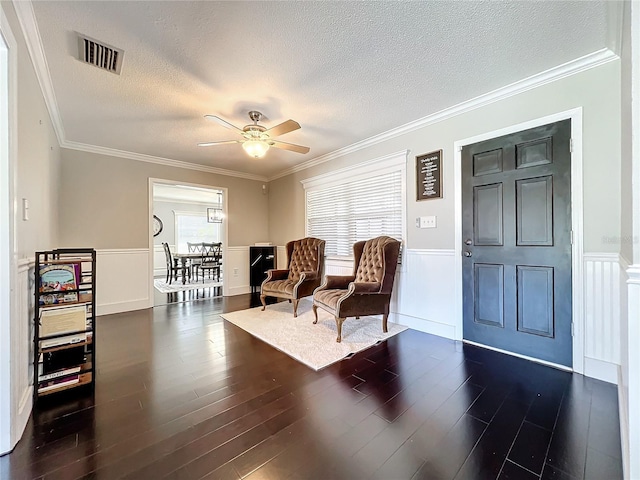 living area featuring a textured ceiling, dark hardwood / wood-style floors, ceiling fan, and crown molding