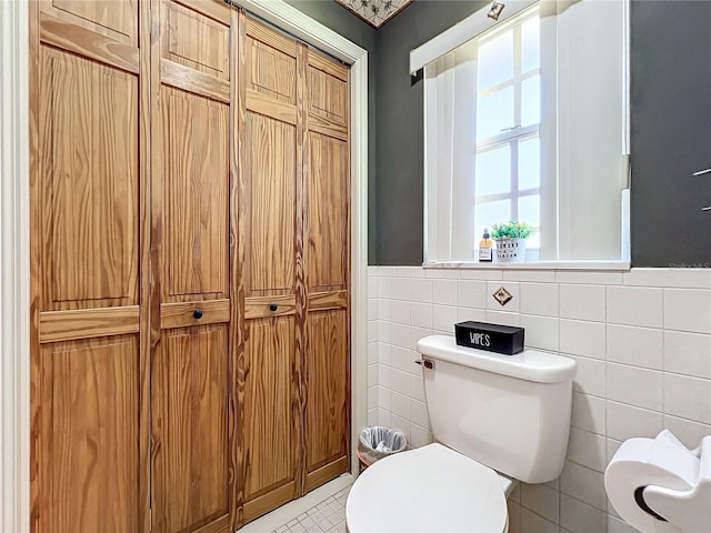 bathroom featuring tile patterned flooring, toilet, and tile walls