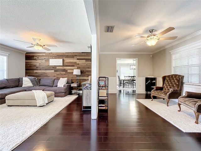 living room with a textured ceiling, dark hardwood / wood-style floors, a wealth of natural light, and wooden walls