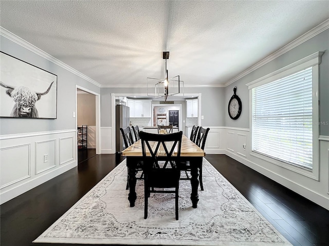 dining space featuring a notable chandelier, dark hardwood / wood-style flooring, ornamental molding, and a textured ceiling