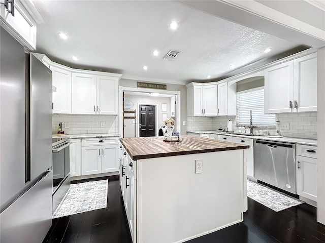 kitchen with white cabinets, butcher block counters, and stainless steel appliances