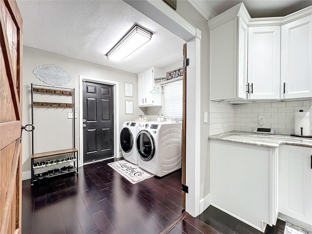 washroom featuring a textured ceiling, cabinets, dark wood-type flooring, and washing machine and clothes dryer