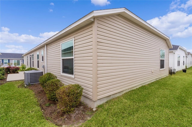 view of side of property featuring central AC and a lawn