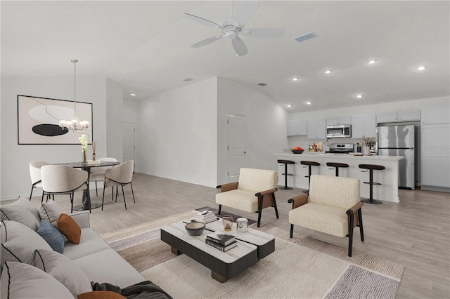 living room featuring ceiling fan with notable chandelier, light hardwood / wood-style flooring, and lofted ceiling