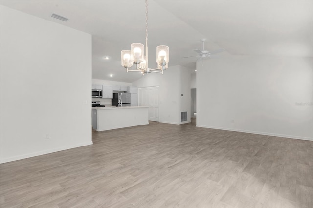 unfurnished living room featuring ceiling fan with notable chandelier, light hardwood / wood-style flooring, and vaulted ceiling