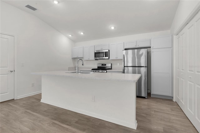 kitchen featuring light wood-type flooring, stainless steel appliances, vaulted ceiling, sink, and a center island with sink