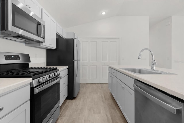 kitchen featuring sink, light hardwood / wood-style flooring, vaulted ceiling, white cabinets, and appliances with stainless steel finishes