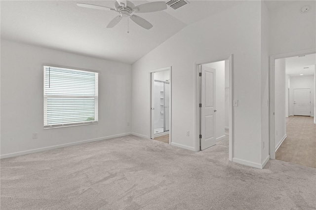 unfurnished bedroom with lofted ceiling, ceiling fan, a spacious closet, connected bathroom, and light colored carpet