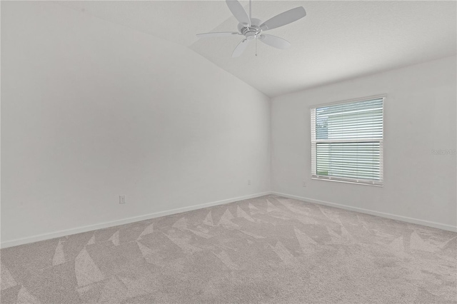 spare room with ceiling fan, light colored carpet, and vaulted ceiling