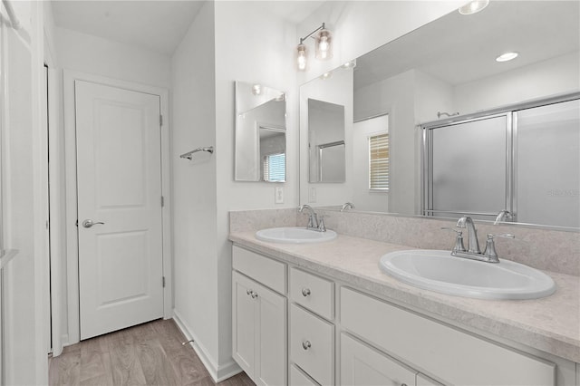 bathroom featuring hardwood / wood-style floors, vanity, and a shower with shower door