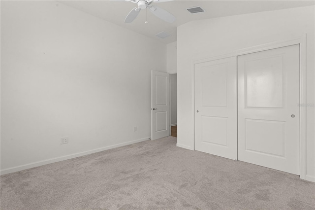 unfurnished bedroom featuring ceiling fan, a closet, light colored carpet, and lofted ceiling