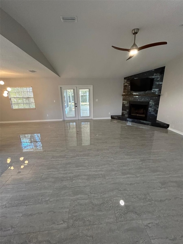 unfurnished living room with ceiling fan, french doors, a fireplace, and vaulted ceiling