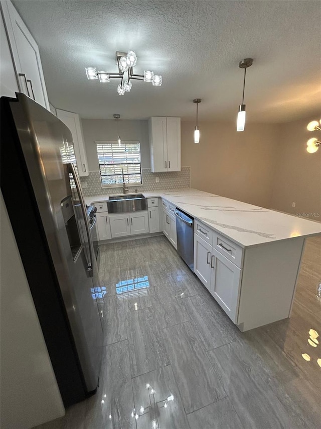 kitchen with pendant lighting, sink, appliances with stainless steel finishes, white cabinetry, and kitchen peninsula