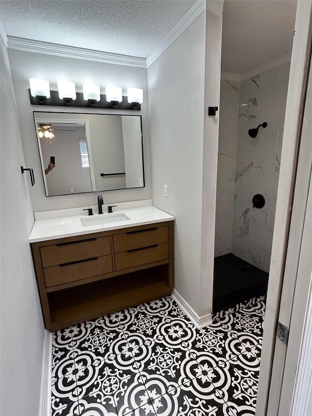 bathroom featuring ceiling fan, a textured ceiling, tiled shower, vanity, and ornamental molding