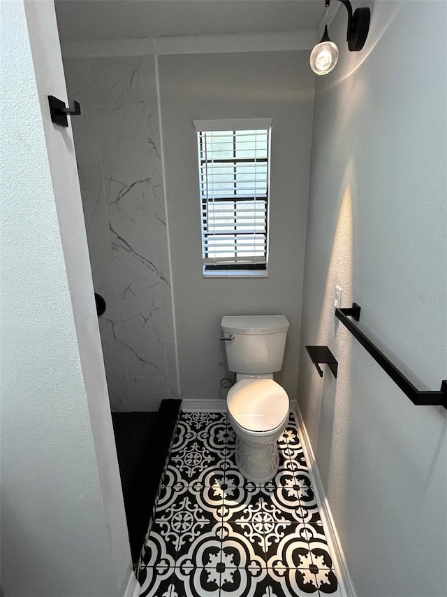 bathroom featuring tile patterned flooring, toilet, a tile shower, and crown molding