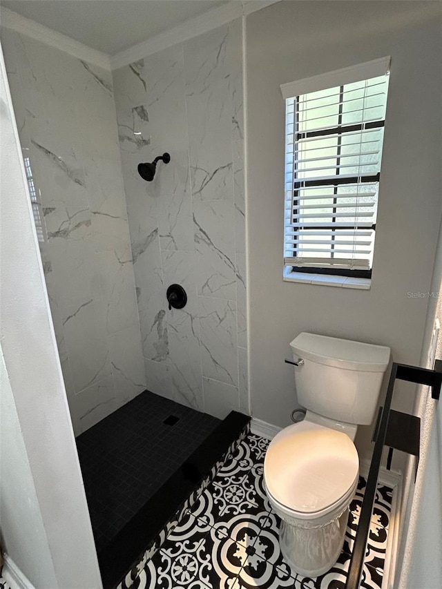 bathroom with a tile shower, crown molding, tile patterned floors, and toilet