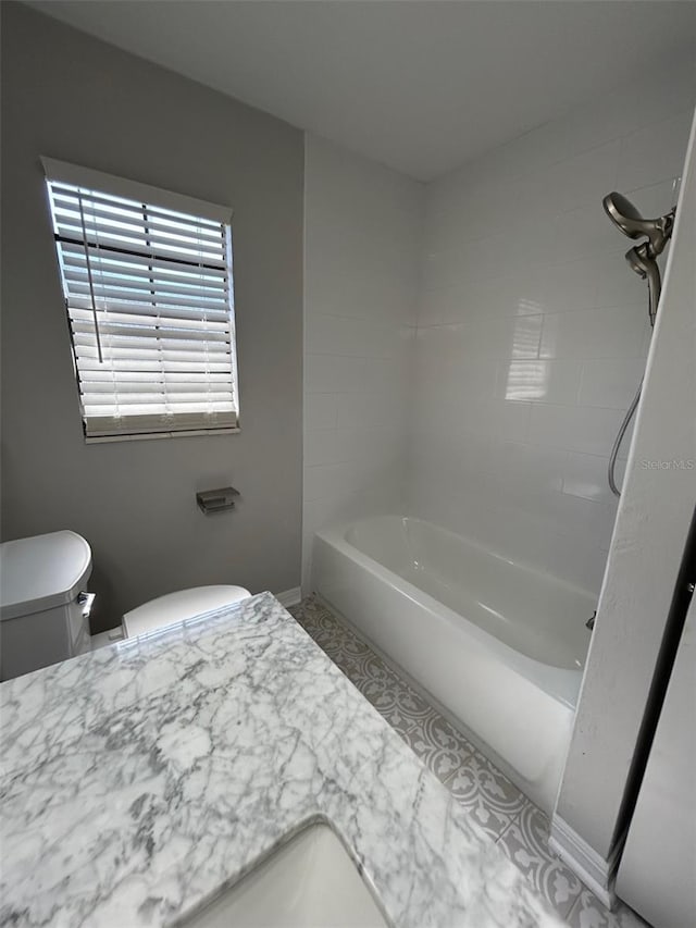 bathroom with toilet and tiled shower / bath