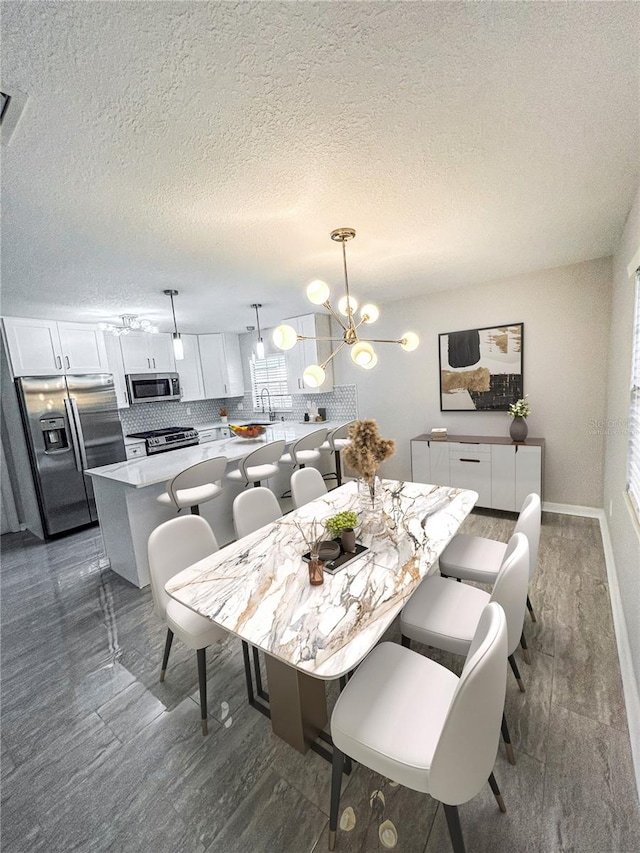 dining area with sink, a notable chandelier, dark hardwood / wood-style flooring, and a textured ceiling