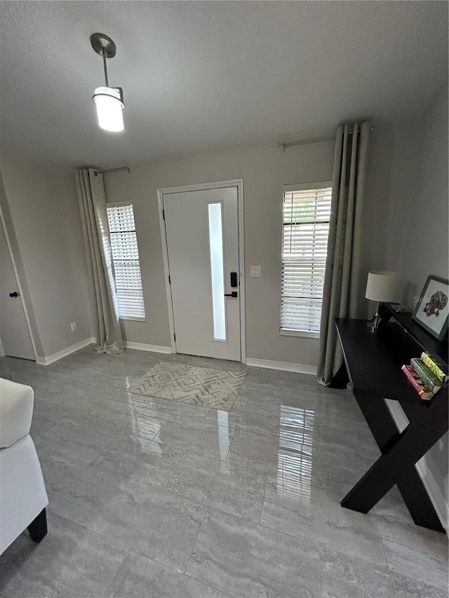 foyer entrance featuring baseboards, a wealth of natural light, and a textured ceiling