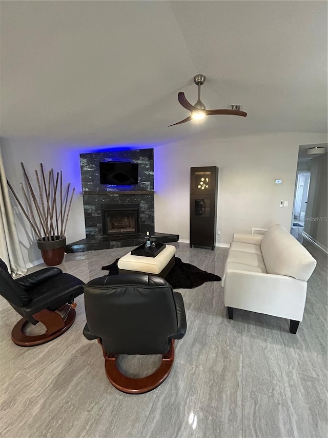 living room with a ceiling fan, visible vents, a tiled fireplace, and baseboards