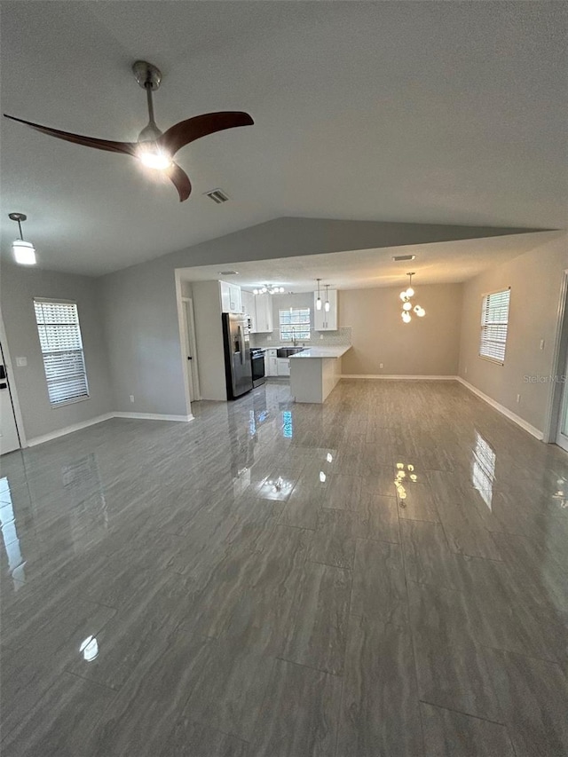 unfurnished living room with plenty of natural light, visible vents, lofted ceiling, and baseboards