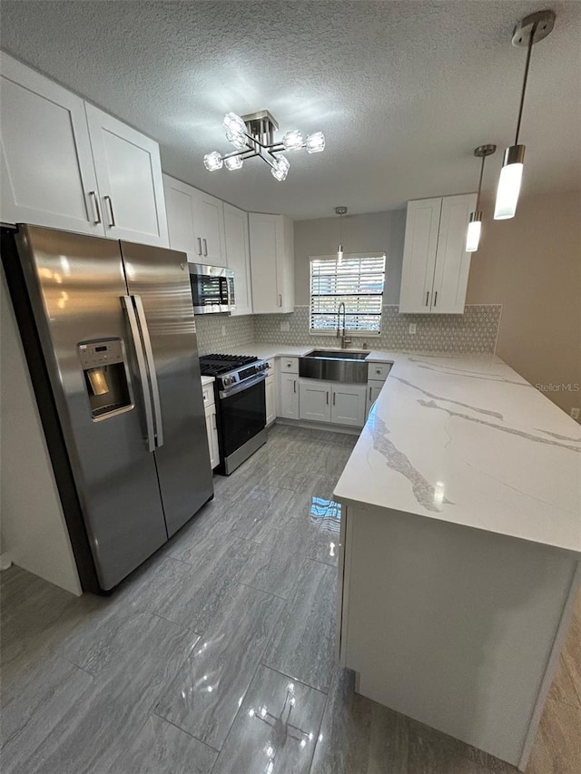 kitchen with stainless steel appliances, white cabinets, backsplash, a sink, and a peninsula