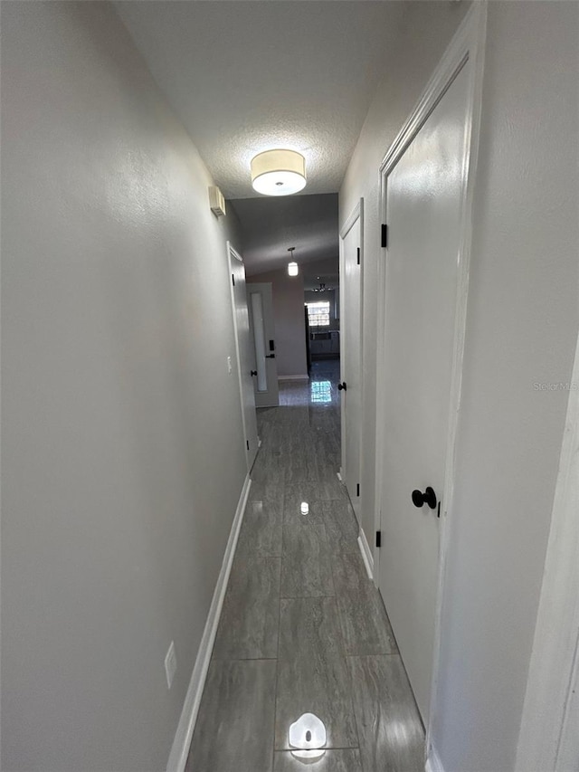 corridor featuring baseboards and a textured ceiling