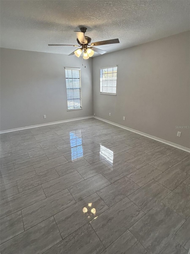spare room with ceiling fan, baseboards, and a textured ceiling