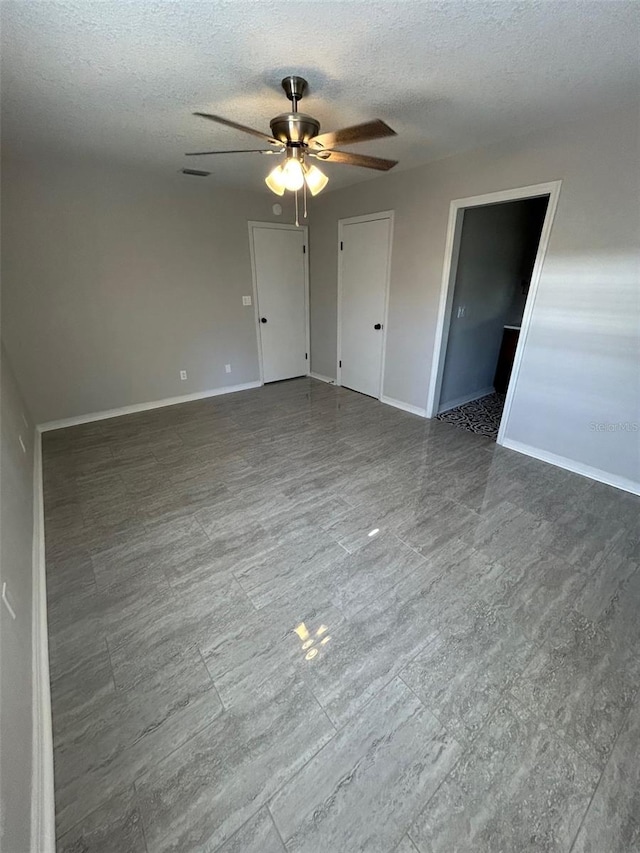spare room with a ceiling fan, baseboards, and a textured ceiling