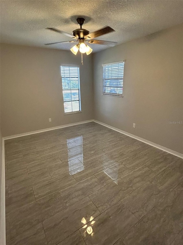 unfurnished room featuring a textured ceiling, a ceiling fan, and baseboards