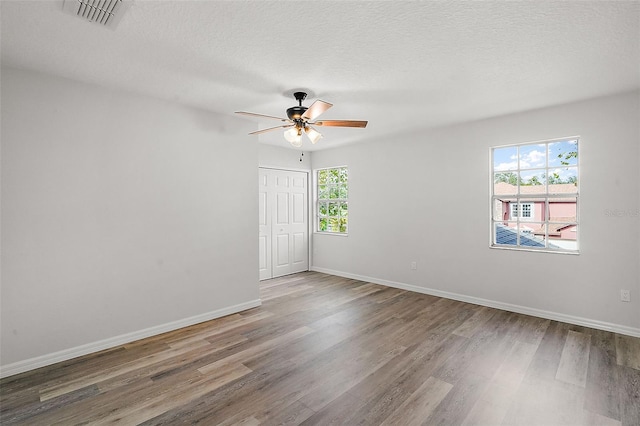 empty room featuring hardwood / wood-style floors, a textured ceiling, a wealth of natural light, and ceiling fan