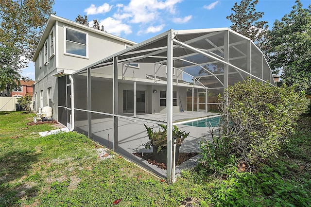 back of property with a lawn, glass enclosure, and a patio