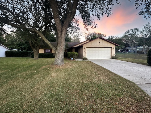 ranch-style home with a garage and a yard