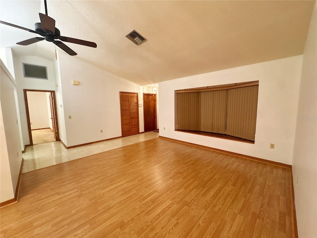 unfurnished room featuring lofted ceiling, ceiling fan, light wood-type flooring, and a textured ceiling