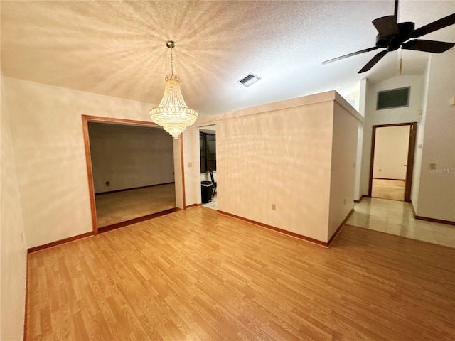 spare room with ceiling fan with notable chandelier, wood-type flooring, a textured ceiling, and lofted ceiling