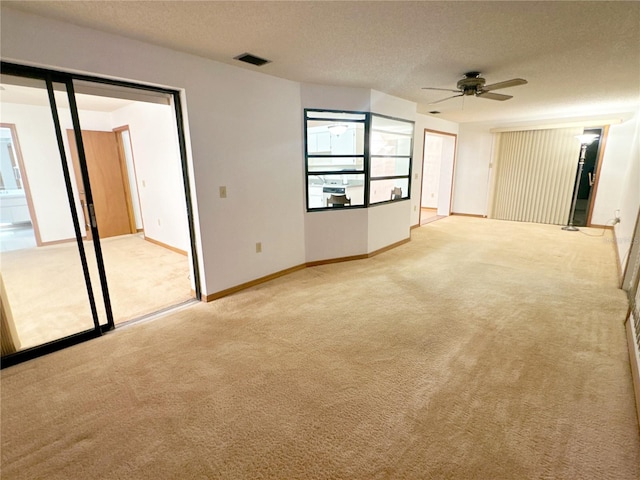 carpeted spare room featuring ceiling fan and a textured ceiling