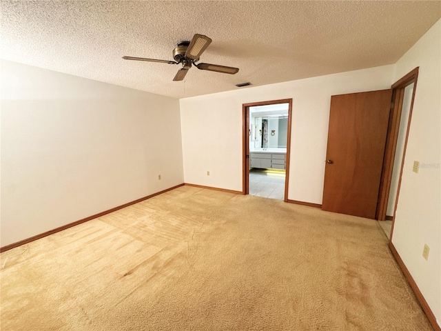 empty room featuring a textured ceiling, light colored carpet, and ceiling fan