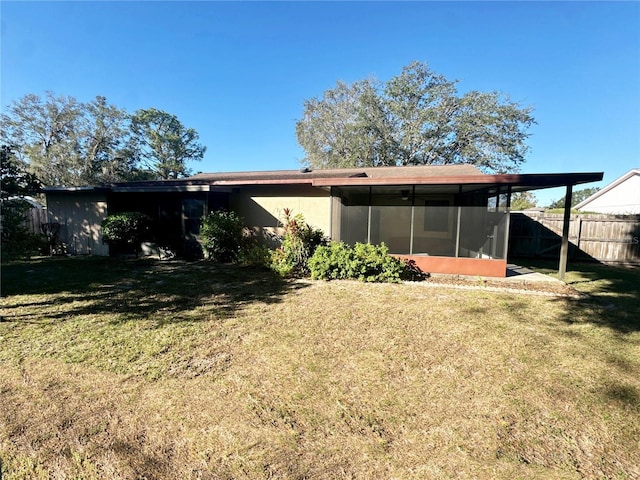 rear view of house featuring a sunroom and a yard