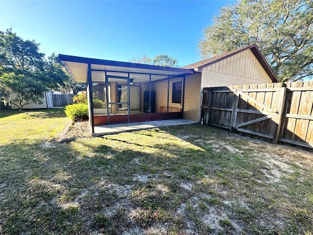 rear view of property with a sunroom, a patio area, and a lawn